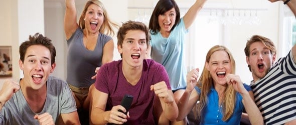 Friends watching sport celebrating a goal in a room