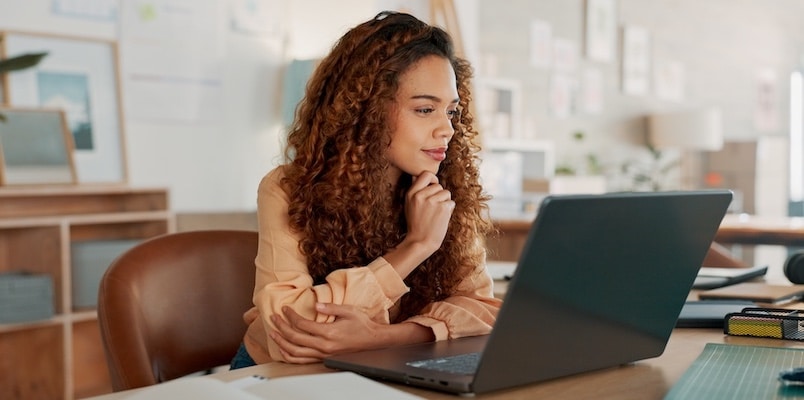 Woman reviewing tax updates on her laptop while learning about changes for 2025 tax year.