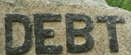 Text written as 'DEBT' over a rock