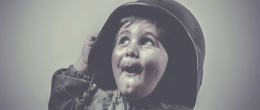 Boy wearing a military helmet looking up with a face expression