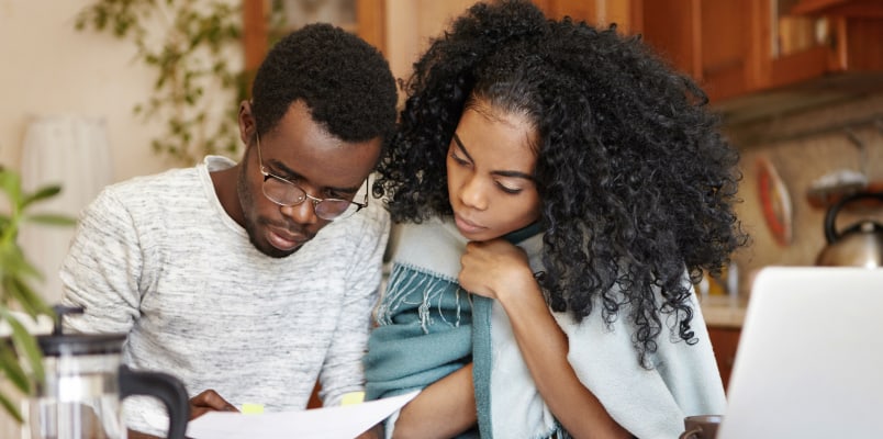 A young couple looking at their tax forms to determine if they owe alternative minimum tax