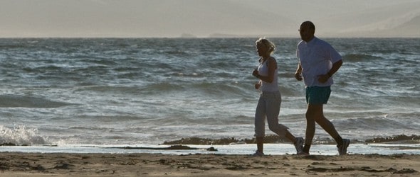 An elderly couple jogging on the beach