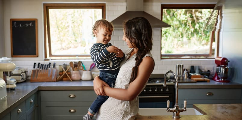 A mother in a white apron holds her smiling toddler.