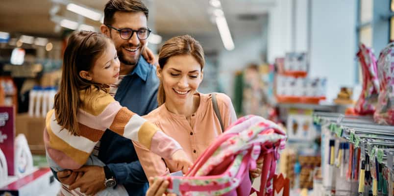 A young couple and their child pick out school supplies while back-to-school shopping