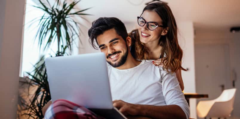 A young boyfriend and girlfriend smile as they look over a tax form before filing taxes