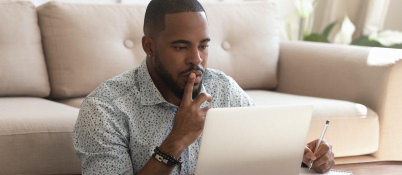 a man looking at the laptop screen while thinking about his taxes