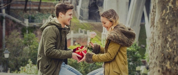 A boy giving his girlfriend a gift on valentines day.