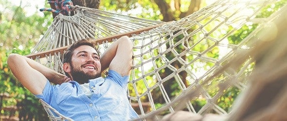 A man sleeping on a hammock and smiling.