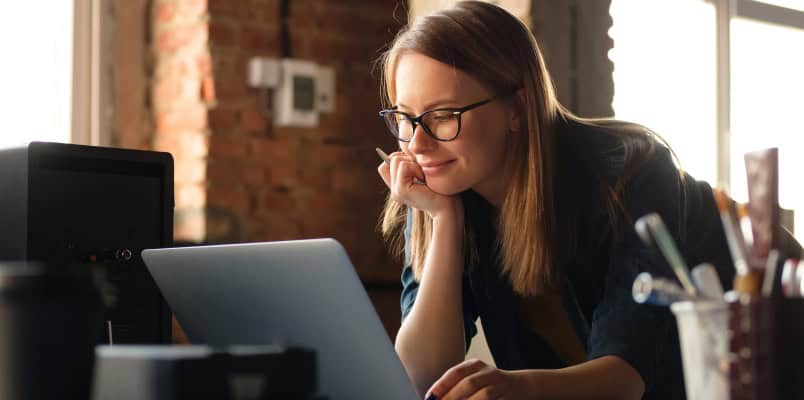 A young expatriate woman researching how to file US taxes while living abroad on her laptop