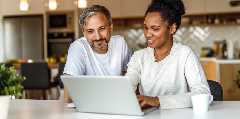 Husband and wife sit down at the kitchen counter together to file their tax return together