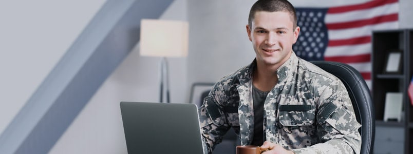 Army officer sitting in front of laptop with a coffee