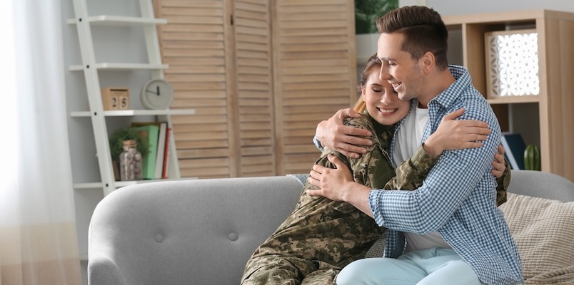 Military couple embracing at home while learning about military spouse state taxes and residency rules.