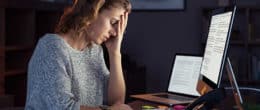 A tensed young woman is sitting at the workstation