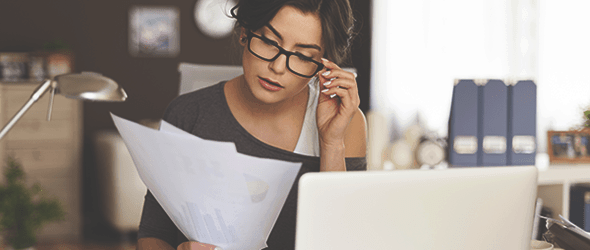 A girl with specs looking at her finance papers.