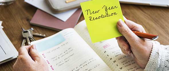 Close-up of a hand holding sticky note with text "new year resolution"