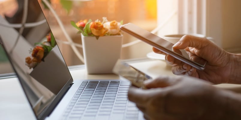 Person using a phone and laptop to make an online payment while learning about PayPal taxes.
