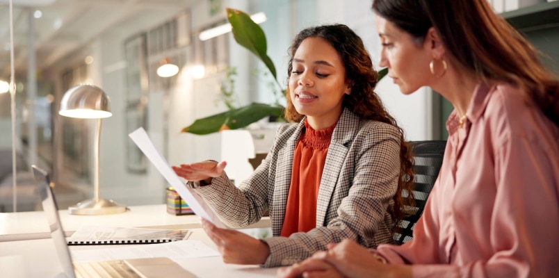 Two women in an office reviewing paperwork together while discussing phantom income and its tax impact.