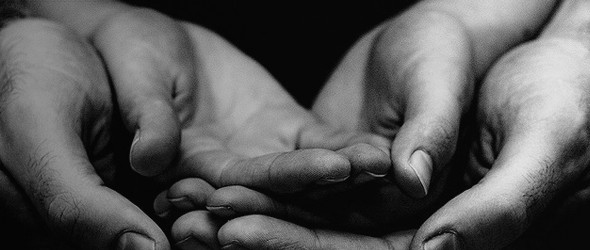 Black and white picture of open hands of a man holding a child's open hands