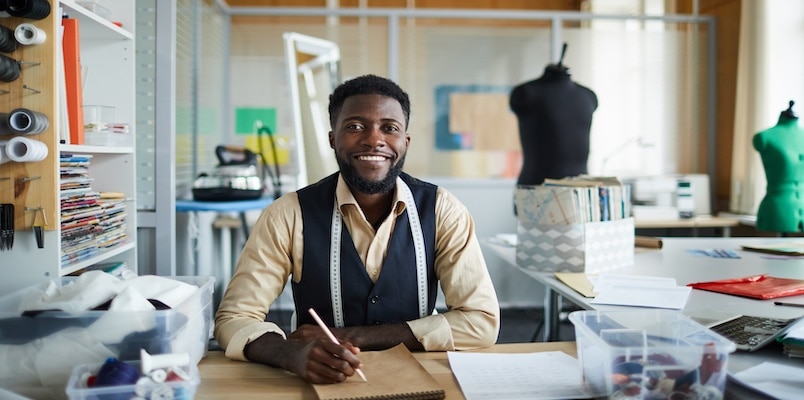 Small business owner working at a desk in a studio while preparing income and expenses for Schedule C.