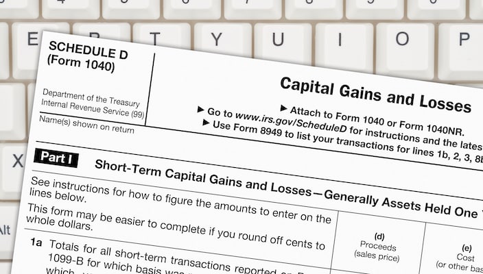 A Schedule D tax form over a keyboard