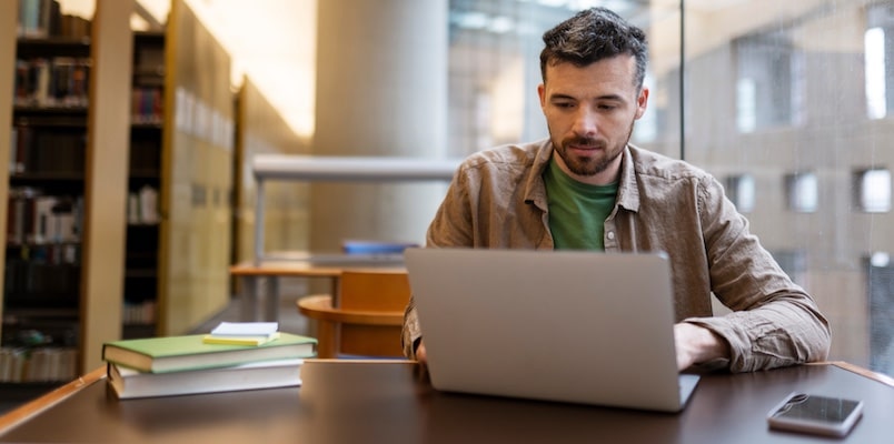 Man researching student loans debt collection updates on his laptop.