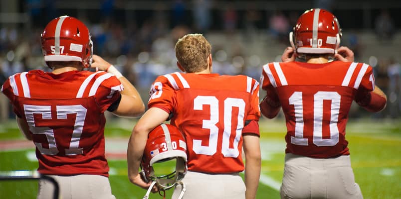 Three athletes on the field in red & white jersey