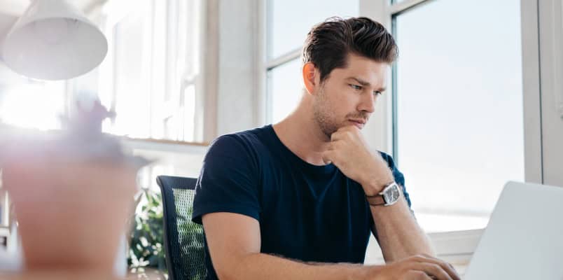 A man stares thoughtfully at his laptop as he reads a guide to tax extensions