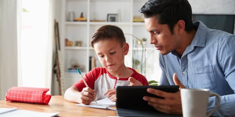A freelance tutor helping a child with his homework