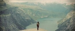 Traveler girl with backpack standing in mountain and enjoying valley