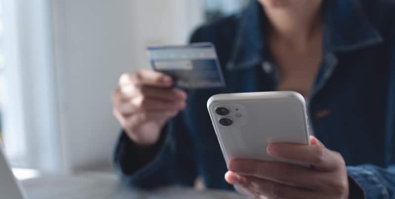 Woman holds her phone and credit card to make a mobile payment