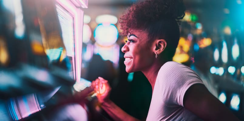 A woman smiles as she looks at a slot machine