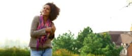 Happy smiling woman with trees and a house in the background