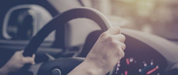 A person holding the steering wheel of their business car.