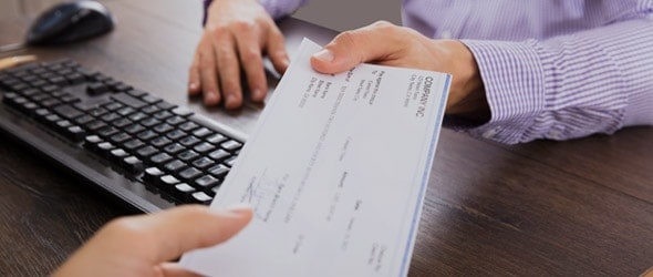 An employer handing over a paycheck to the employee