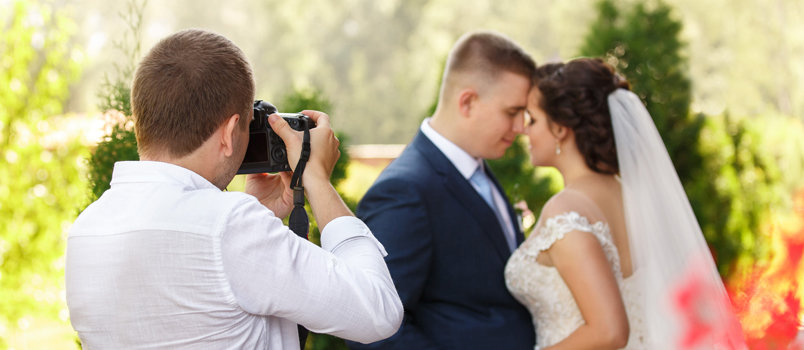 A photographer clicking photo of a bride and groom