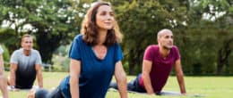 Happy men and smiling women in yoga class doing exercise outdoor