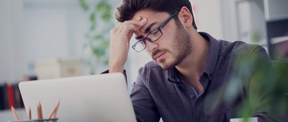 Stressed man in front of a laptop because of an IRS identity theft