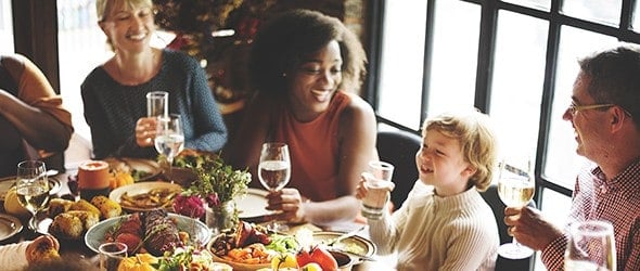 A family enjoying their Thanksgiving meal along with their friends